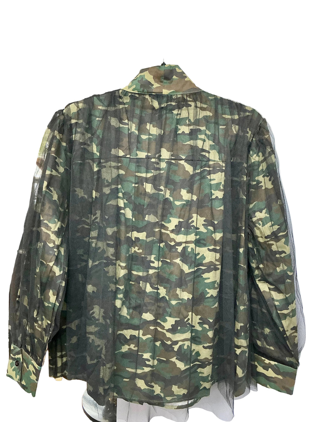 Back view of camouflage-patterned shirt with a white wall background