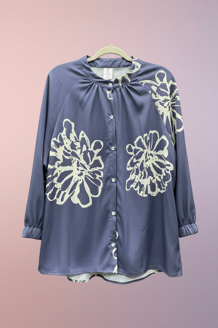 A long-sleeve button-front blouse in cauliflower blue with large cream floral line-art prints, hanging on a hanger.
