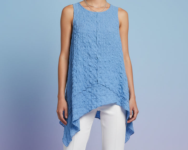 A light blue sleeveless top with a ruffled, crinkled pattern and an asymmetrical handkerchief hem on model