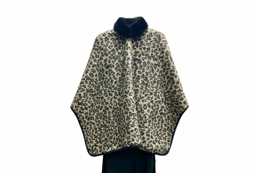 Leopard print cape with black fur trim on a hanger.
