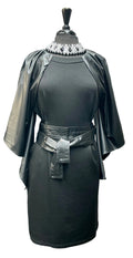 Black dress with flowing vegan leather sleeves and belt on a mannequin against a gray wall.
