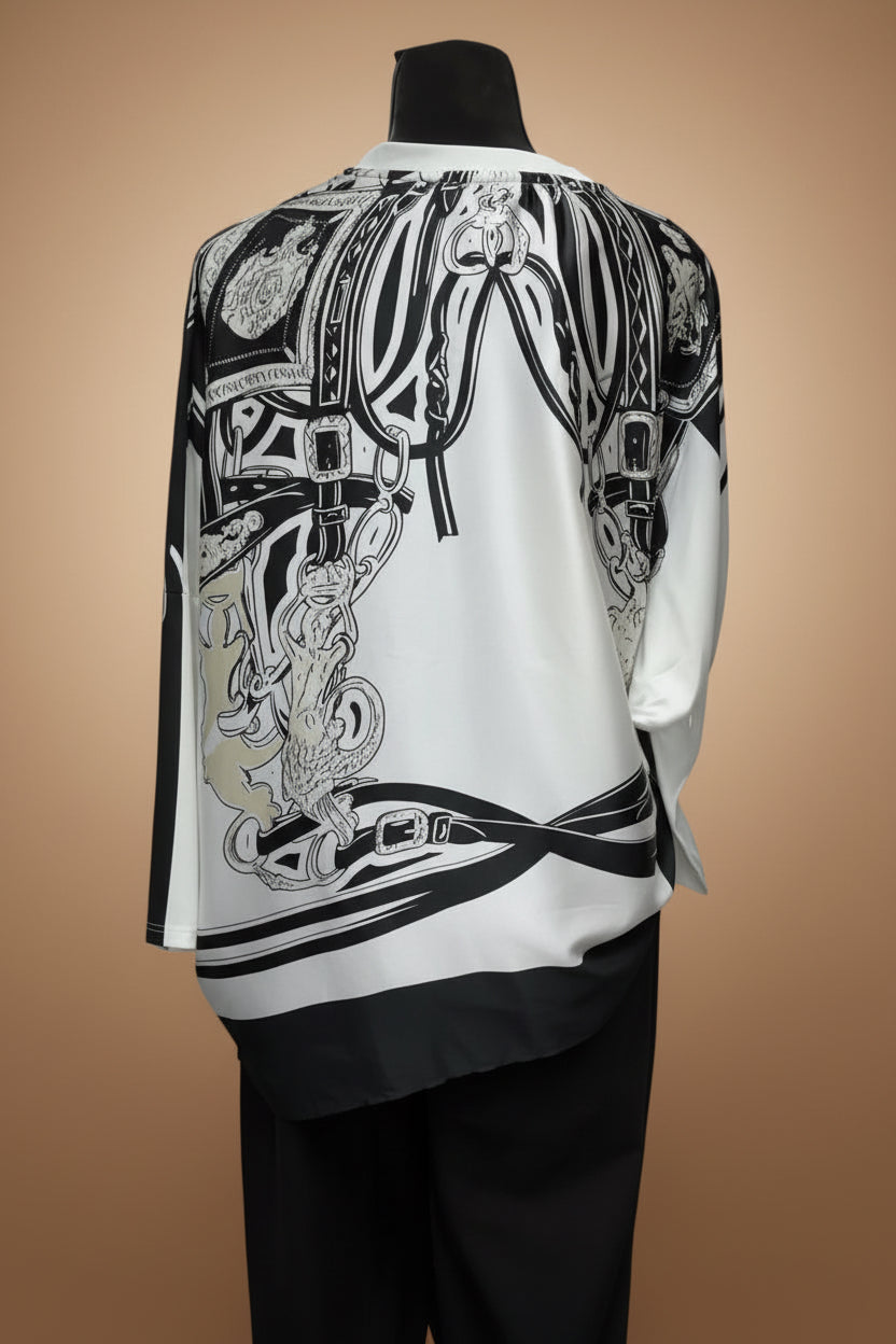 A white long-sleeve shirt with a large black and gray graphic print featuring chains and ornate details, shown on a mannequin in retail setting.