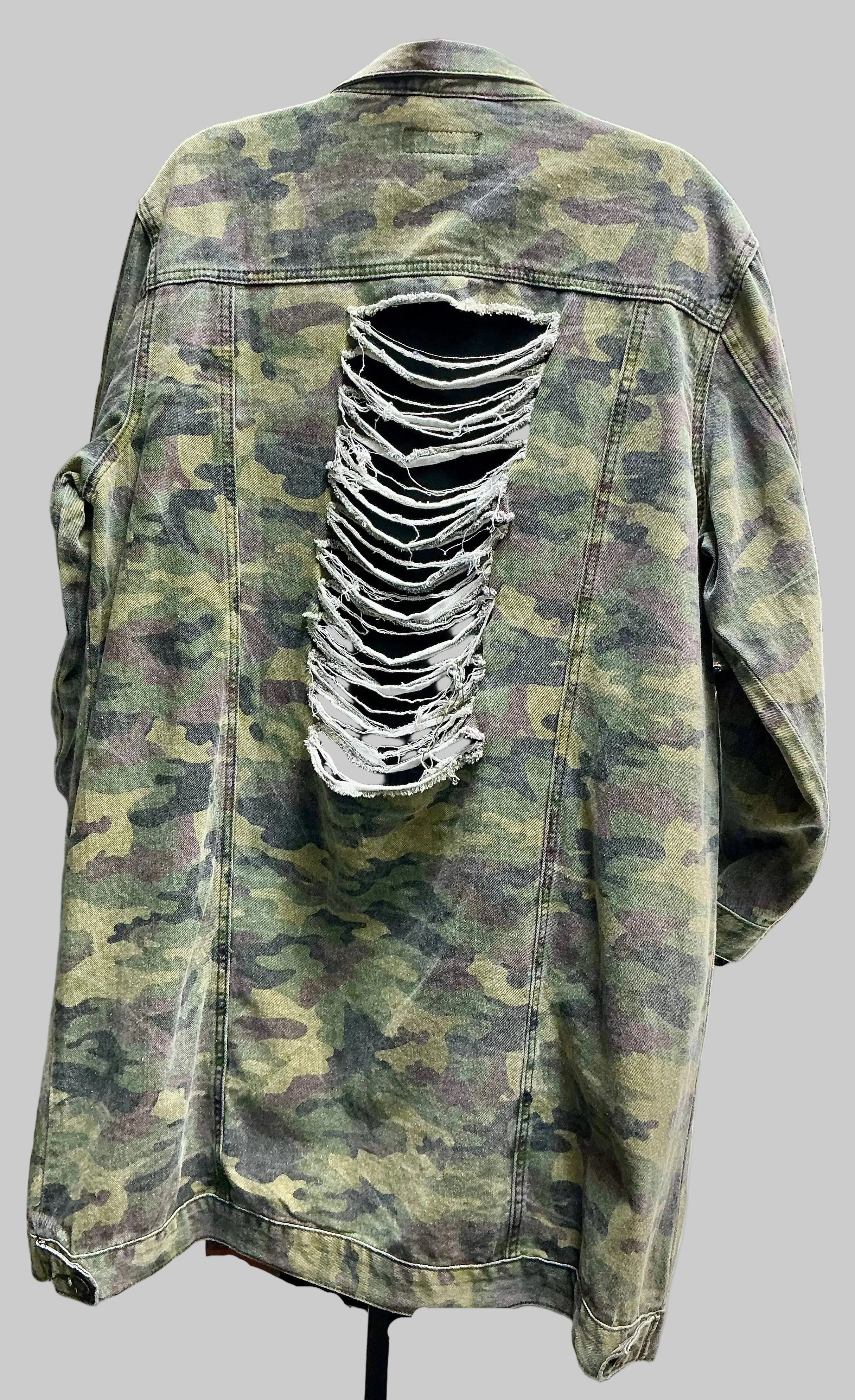 Back view of denim camouflage jacket with a large rip